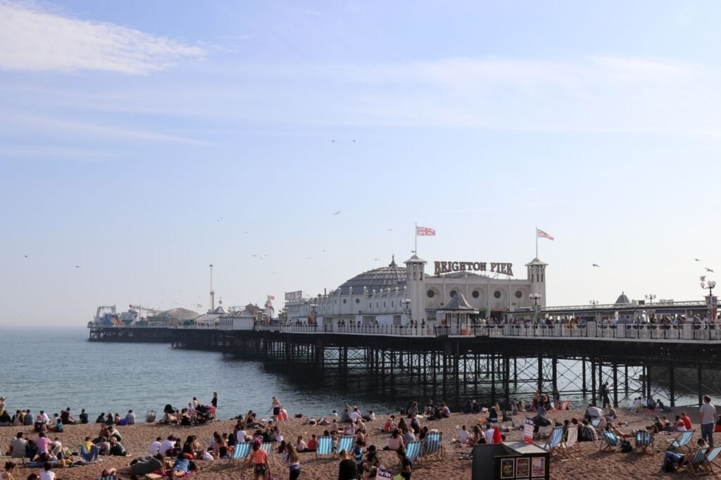 A lively scene of Brighton Pier in England with people enjoying the sunny beach.